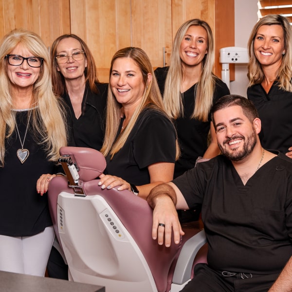 A photo of Prestige Dental team gathered around a dentist's chair