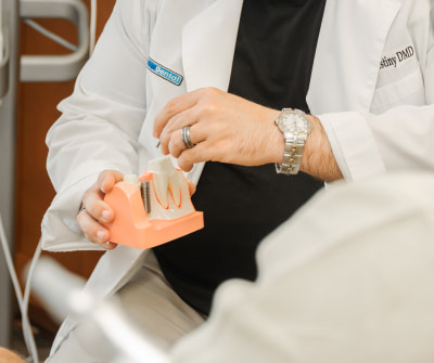 Photo of Dr. Falestiny holding a dental implant