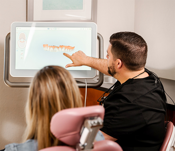 Dr. Falestiny showing a patient a prototype of a dental implant